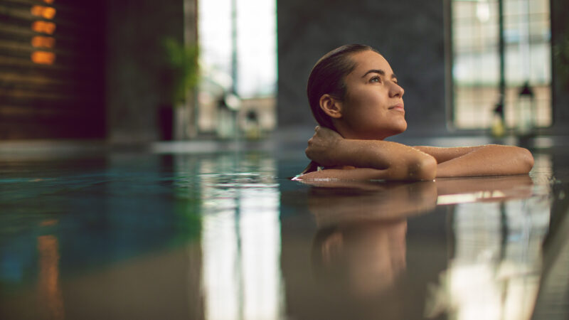 Portrait of beautiful woman relaxing and enjoying in swimming pool. Photo taken under natural light