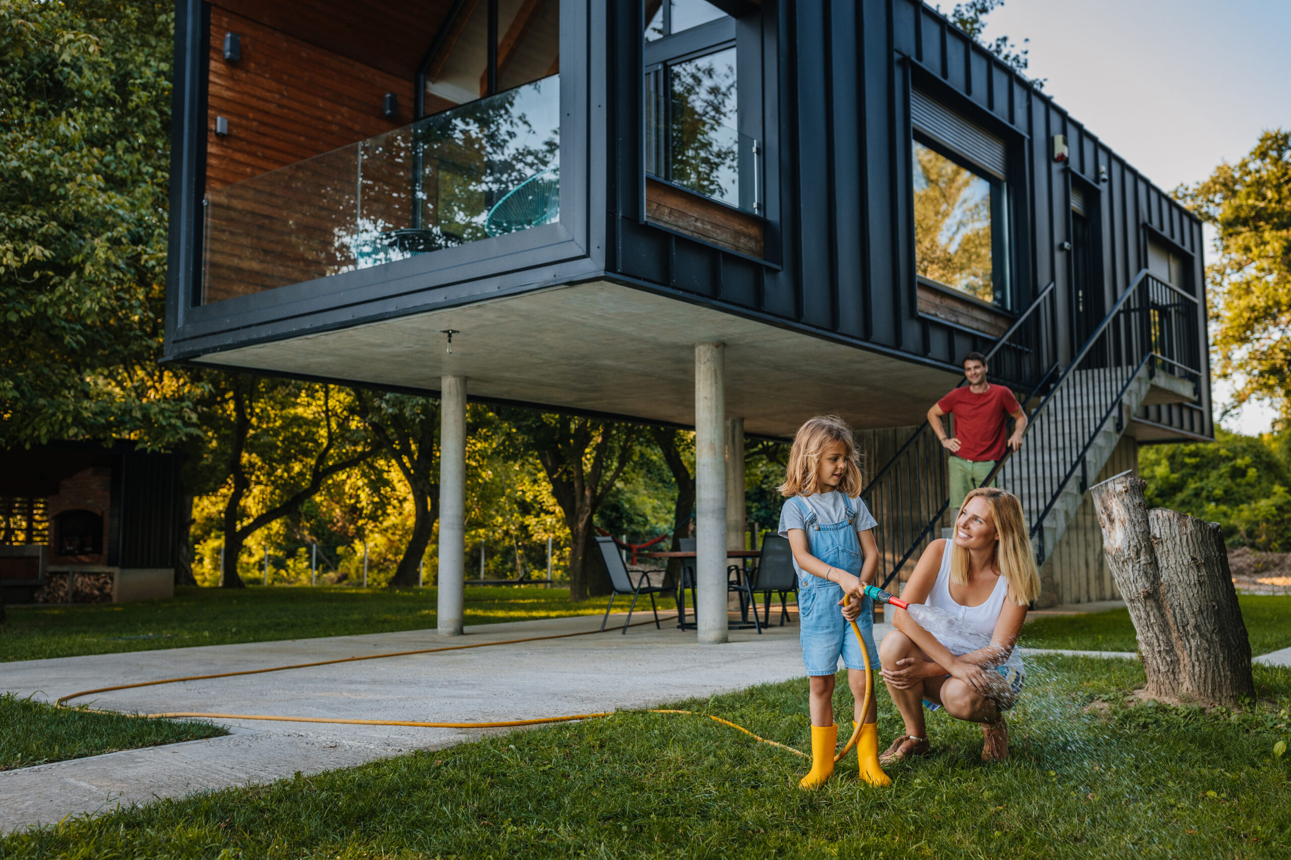 Child with hose and parents on a fire resistant lawn