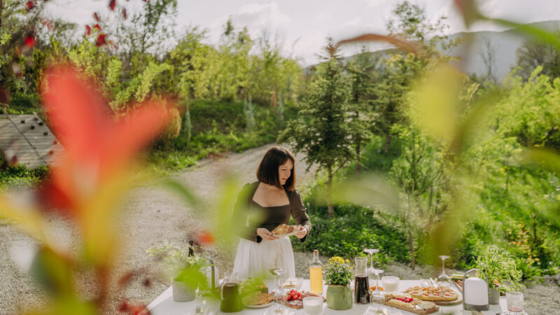 Photo of a woman setting the table for an outdoors dinner party.