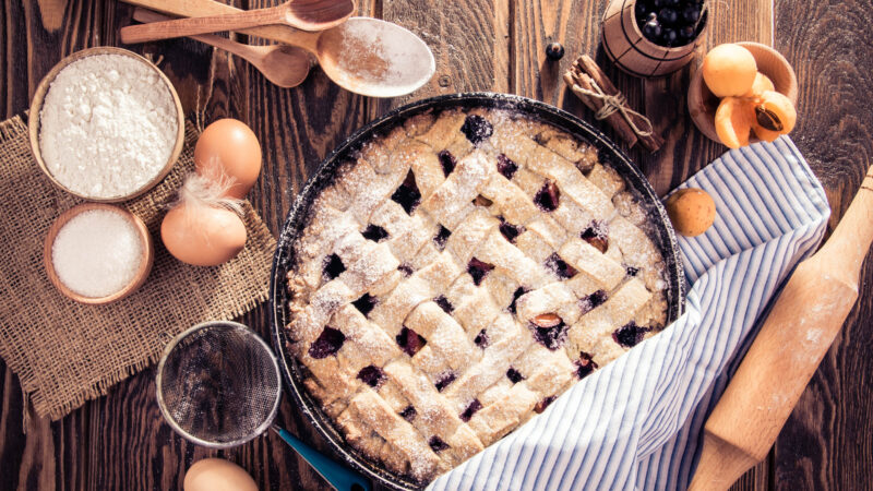 Black currant and apricot pie with ingredients on wooden table