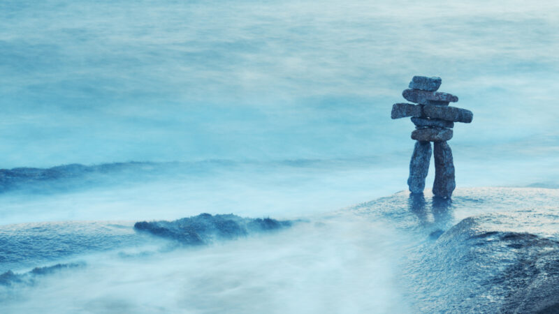 An inuksuk made of granite boulders awash in the Atlantic Ocean.
