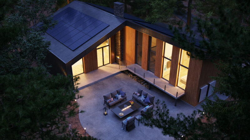Off grid homes equipped with solar panels and an energy storage wall battery during dusk.